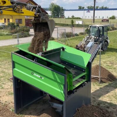 Närbild på när grävmaskin tippar skopa i ett sorteringsverk